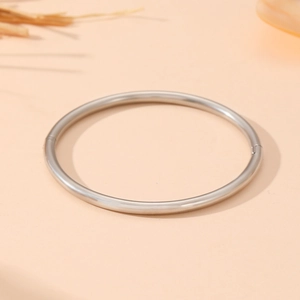Detailed macro view of the silver stainless steel hinged clasp on this smooth metal bangle