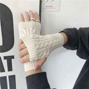 Detalle de guantes sin dedos de punto trenzado blanco que muestran textura de invierno