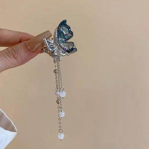 Détail de la pince à cheveux papillon argentée avec ailes bleues et longs pompons perlés