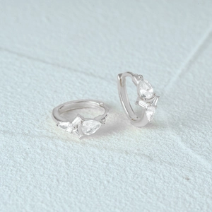 Macro shot of silver geometric earrings with sparkling clear zircons in a hoop design