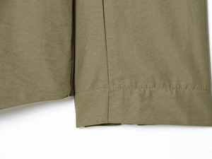 Gros plan du pantalon vert olive montrant la texture du tissu et les coutures soignées