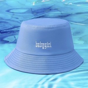 Dettaglio del ricamo bianco babygirl su un cappello a secchiello in tela celeste