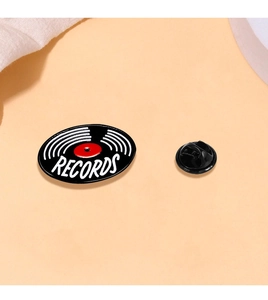 Macro detail of retro vinyl record enamel pin with RECORDS text and butterfly clasp