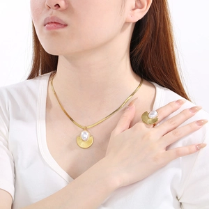 Dettaglio della collana e dell'anello dorati a ventaglio con intarsi di perle bianche