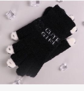 Detail of black knit winter gloves featuring white Cute Girl embroidery and snowy ice props