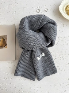Primo piano di una sciarpa in maglia spessa grigio scuro con etichetta decorativa bianca