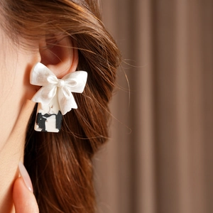 Gros plan de boucles d'oreilles nœud blanc avec pendentifs marbrés sur un mannequin