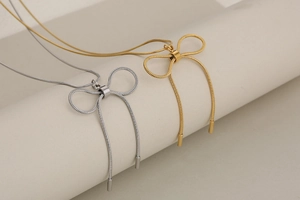 Detailed shot of gold and silver bow pendant necklaces with fine snake chain textures