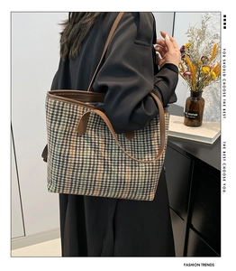 Detail of retro plaid tote bag with brown leather trim and shoulder straps on display