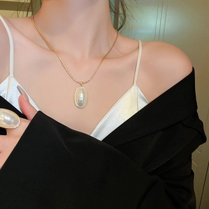 Détail du collier de perles ovales plaqué or et de la bague assortie sur un mannequin