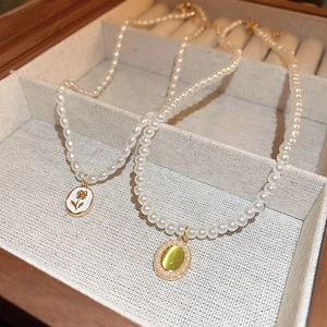 Vintage pearl necklace featuring floral enamel and green cat-eye pendants in a wood box