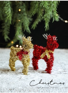 Festive gold and red reindeer statues with glitter finish and bells in a snow scene