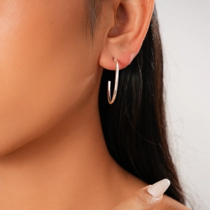 Close-up of a minimalist silver geometric C-shaped stud earring on a model ear