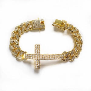 Macro view of gold-plated Cuban chain bracelet with iced-out cross and crystal pave