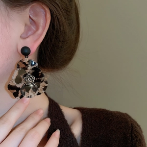 Detail of leopard print flower C-shape earring featuring black rose relief on a model