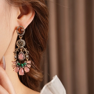 Detailed close-up of a vintage floral water drop earring with crystals on a model