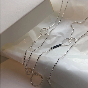 Elegant s925 silver beaded necklace with round and rectangle pendants on a textured display