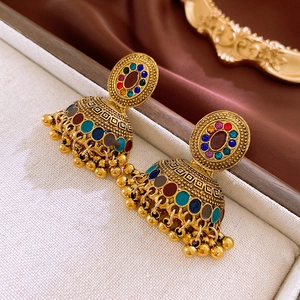 Dettaglio ravvicinato di orecchini Jhumka vintage dorati con accenti in smalto colorato
