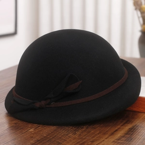 Detail of elegant black wool felt hat with brown ribbon bow on a wooden surface
