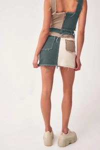 Detail view of denim mini skirt showing back multi-color patchwork and frayed hem edges