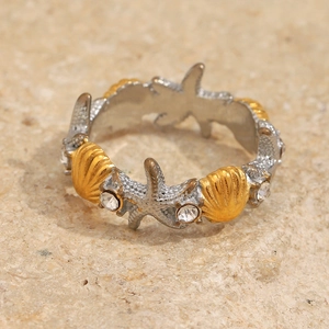 Macro shot of 18K gold starfish and seashell ring with sparkling zircon inlays