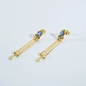 Detail of gold tassel earrings with pear-shaped blue gemstones and zircon inlay