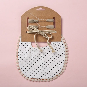 Détail du lot de bavoirs bébé à pois noirs, dentelle à pompons et bandeaux assortis