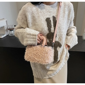 Detailed close-up of a pink faux wool box bag held by a model in a cafe setting