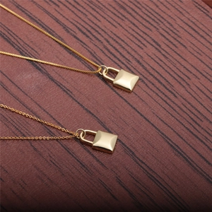 Minimalist gold lock pendant necklace set with delicate chains on wood surface