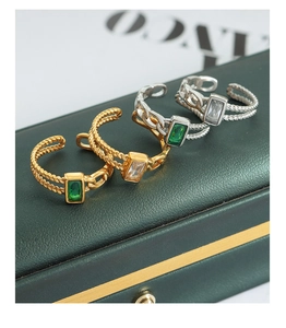 Détail macro de bagues ajustables avec zircons verts et blancs sur coffret en cuir