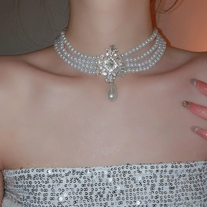 Gros plan d'un élégant ras-du-cou en perles multicouches avec pendentif diamanté argenté