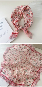 Detailed macro view of pink floral cotton linen scarf with soft flower patterns and red border