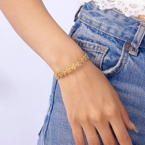 Close-up of a gold-plated stainless steel hollow floral pattern bracelet on a woman's wrist