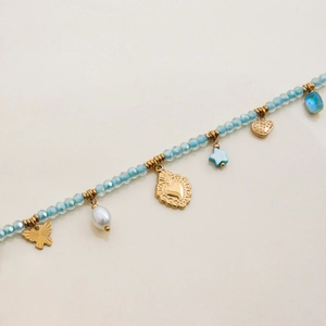 Detail of blue faceted bead necklace with butterfly, pearl, and gold heart charms
