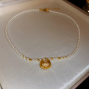 Macro detail of Chinese Fu lucky bag pendant with white pearls on a textured jewelry box