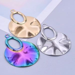 Close-up of wavy geometric pendant charms in gold, silver, and rainbow steel plating