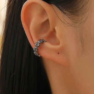 Macro view of vintage silver skull ear cuff in punk gothic style on model ear