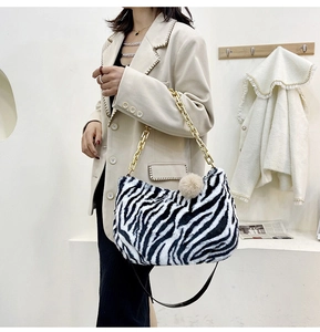 Close-up of zebra print faux fur tote bag with gold chain strap and fluffy pompom detail