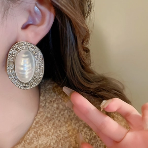 Macro side view of vintage silver textured oval earrings with baroque pearl on a model