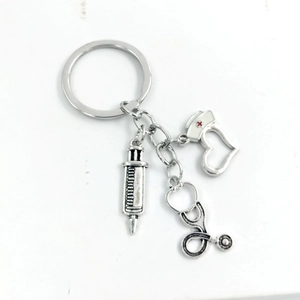 Macro detail of silver medical keychain with syringe, stethoscope and heart nurse hat charms