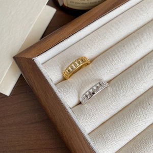 Detail of silver and gold hollow olive leaf rings displayed in a wooden jewelry box