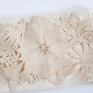 Detail der Blumenstickerei und Mesh-Einsätze an einem beigen Neckholder-Kleid