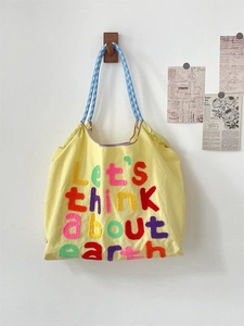Detail of embroidered Let's think about earth text on yellow canvas tote bag