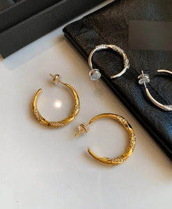Macro view of C-shaped gold and silver earrings with twisted design and zircon inlay