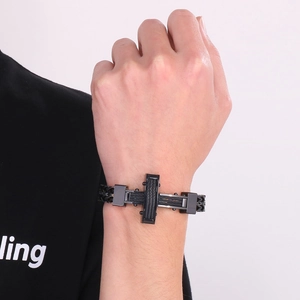 Macro detail of men's matte black cross bracelet showing textured metal and woven band