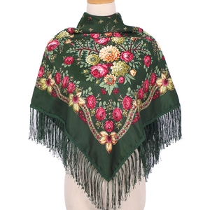 Close-up of ethnic floral patterns and tassel fringe on a dark green silk scarf