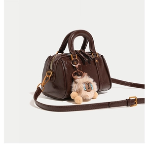 Detailed side view of dark brown high-gloss Boston bag with cute plush sheep pendant