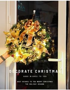 Detail of glowing Christmas wreath with golden bows, LED lights, and Merry Christmas sign
