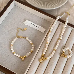 Détail d'un ensemble de bijoux en perles d'eau douce avec perles dorées sur plateau