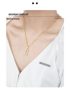 Detail showing a gold rectangular open frame pendant set with small white pearls on a chain